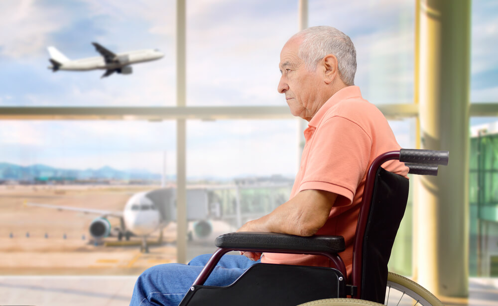 patient senior on a wheelchair at a airport looking outside