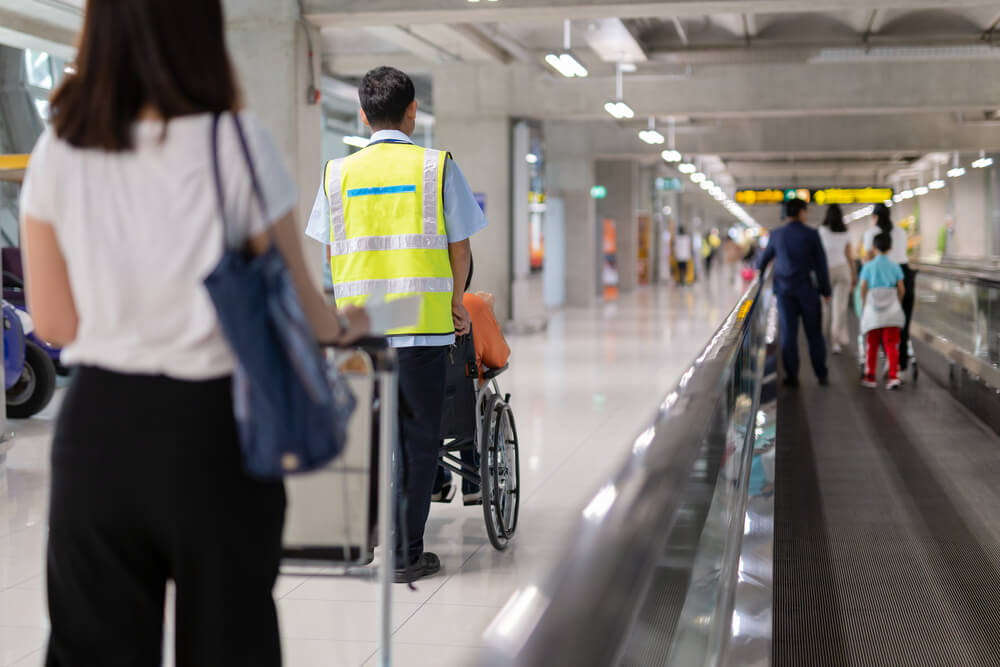 Caretaker pushing elderly people on wheelchair in the airport.